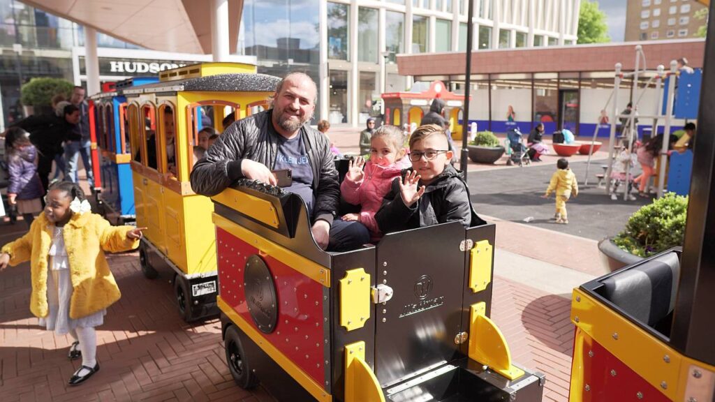 Trackless Wattman Mini Express train giving rides inside a busy US shopping mall