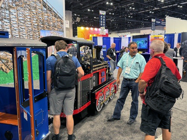 Wattman USA team speaking with clients next to a display train at IAAPA Expo 2025 in Orlando