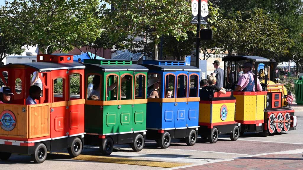 Wattman Mini Express train driving through a US city park surrounded by families