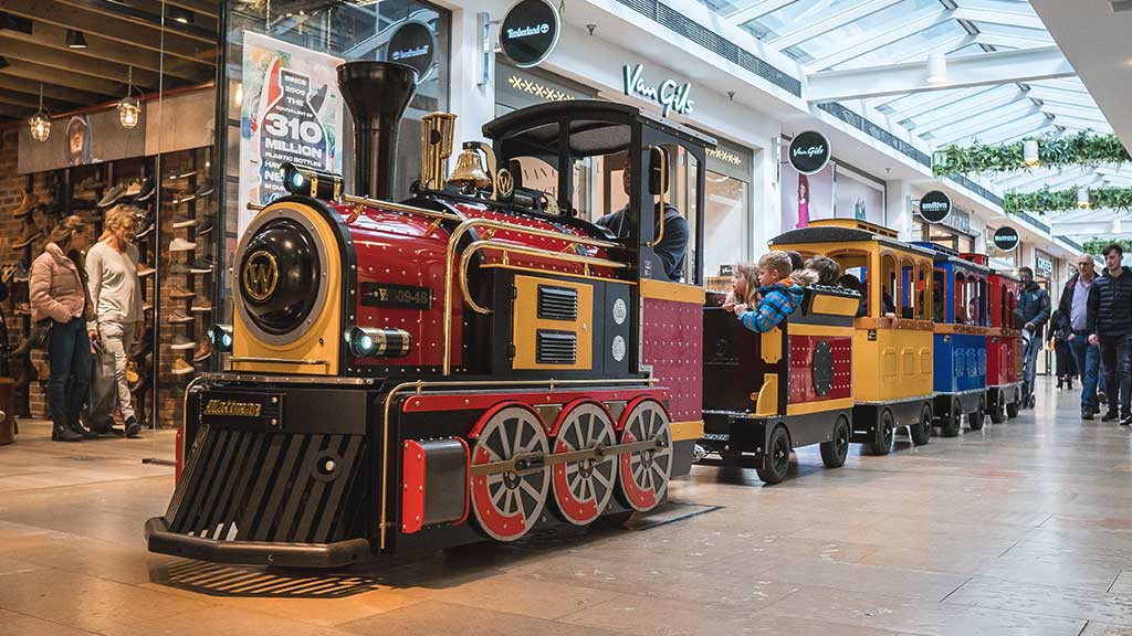 Trackless Wattman Mini Express train giving rides inside a busy US shopping mall