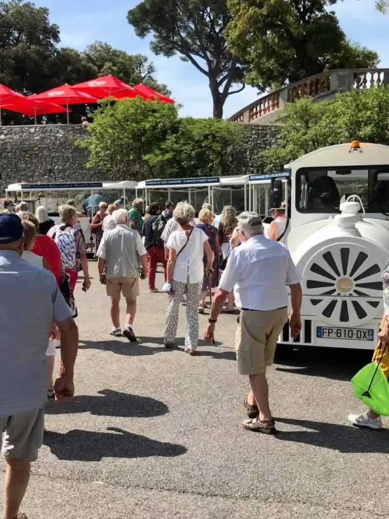White Deltrain road train with passenger wagons transporting tourists at an outdoor venue in the United States
