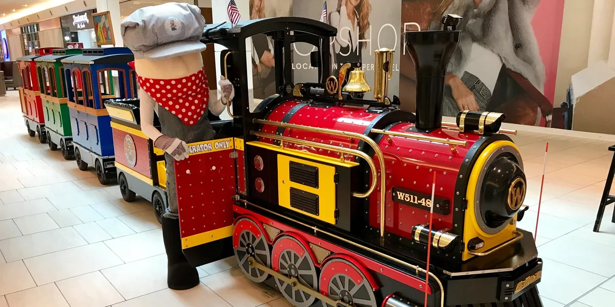 Wattman electric trackless train operating inside a U.S. shopping mall with families and children